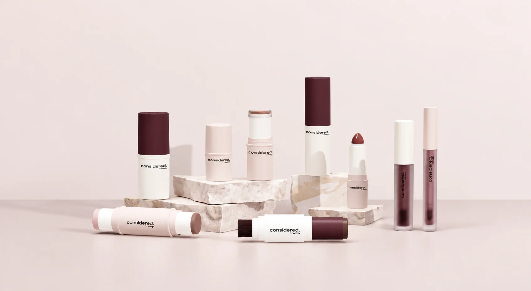 Mono-material makeup packaging collection arranged on pale stone plinths